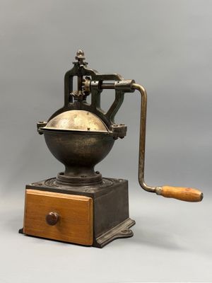 un vieux moulin à café avec un manche en bois sur fond gris