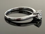 a close up of a diamond ring on a reflective surface