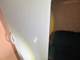 a white refrigerator that is in a room with a black chair
