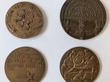 four bronze medals of various sizes and shapes on a white surface