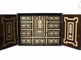 a black and gold cabinet with a mirror on it