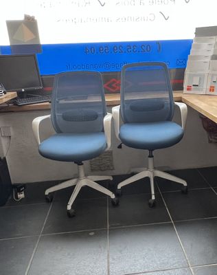 deux chaises de bureau bleues placées devant un bureau d'ordinateur