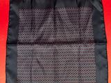 a black and red silk pocket square on a red background