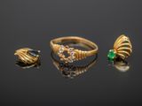 two gold rings and a ring with green stones on a black surface