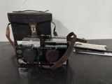an old camera sitting on top of a table next to a bag