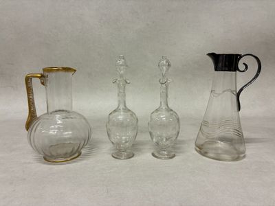 trois vases en verre et une carafe en verre posés sur une surface blanche