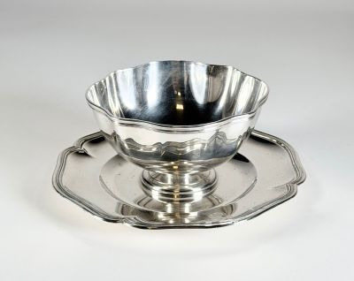 une tasse et une soucoupe en argent posées sur un plateau en argent