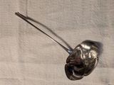 une cuillère en argent avec un manche en métal posée sur une nappe blanche