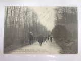 a black and white photo of a group of people riding horses down a dirt road