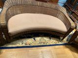 a wicker bench with a cushion on it in the middle of a room