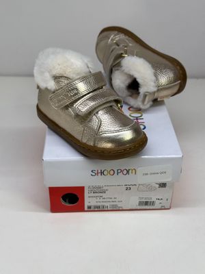 un petit chat blanc assis sur une chaussure dorée
