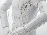 a white statue of a robot holding a piece of equipment