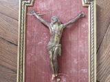 a gold crucifix on a red wall on a wooden floor