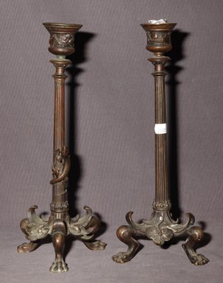 une paire de bougeoirs anciens en bronze sur socles, sur fond gris