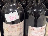 bottles of red wine are lined up on a shelf in a store
