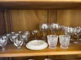 many glasses and plates on a shelf in a cabinet