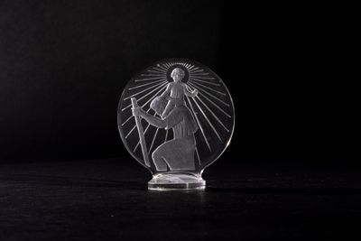 a clear glass figurine of a person holding a cross