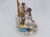 a figurine of a woman sitting on a chair with a harp