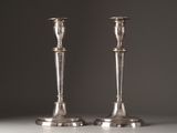 pair of silver candlesticks on a table against a grey background