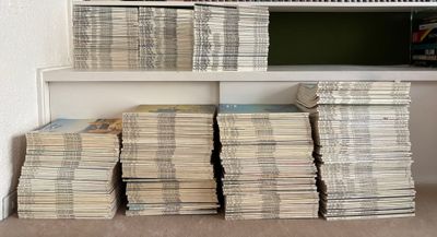 many stacks of newspapers stacked on a shelf in a room