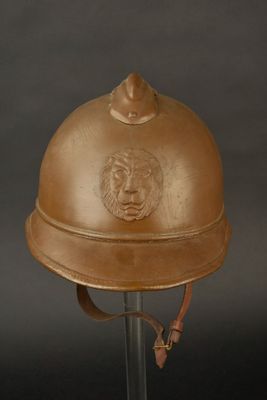 un vieux casque orné d'une tête de lion, posé sur un socle métallique