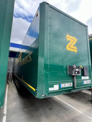 a man standing next to a green truck in a parking lot
