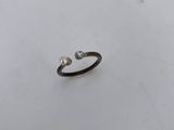 a small ring with two pearls sitting on top of a white surface