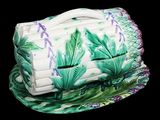 une boîte en céramique verte et blanche ornée de fleurs violettes