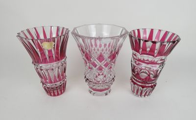 trois vases en verre rose posés les uns à côté des autres sur une surface blanche