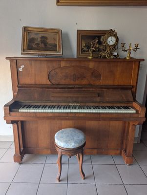 un piano et un tabouret dans une pièce où est accrochée une horloge au mur