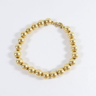 a close up of a gold beaded bracelet on a white background