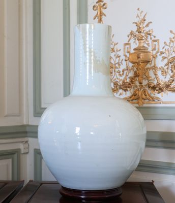 un vase blanc posé sur une table devant un mur