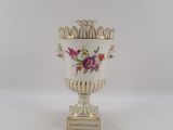 a white vase with flowers on it sitting on a table