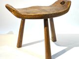 un petit tabouret en bois à deux pieds posé sur une surface blanche