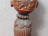 un petit vase en bois posé sur un socle, sur une surface rose