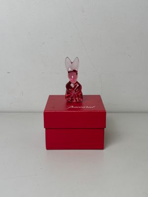 une petite boîte rouge sur laquelle est posée une figurine de souris en verre