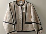 beige and black jacket hanging on a hanger on a wall
