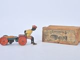 toy figurine of a man on a tractor pulling a cart with a box in the background