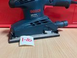 un gros plan d'une ponceuse orbitale Bosch posée sur une table en bois