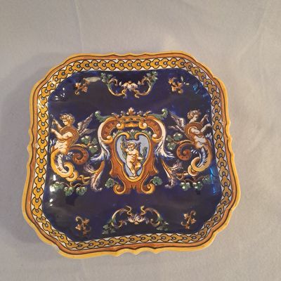 une assiette bleue et dorée sur laquelle est représentée une femme