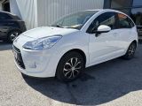 une voiture blanche garée devant un immeuble, à côté d'autres voitures