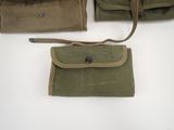 three military pouchs are lined up on a white surface