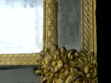a mirror with a gold frame on a black wall