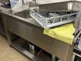 un évier en acier inoxydable dans une cuisine professionnelle, avec une serviette jaune posée sur le plan de travail