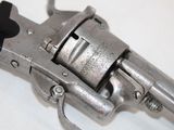 a silver revolver with a black handle on a white surface