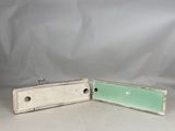 two pieces of white and green painted metal on a white surface