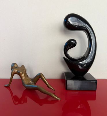statue d'une femme allongée sur une table rouge, à côté d'une sculpture représentant une femme