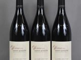 Trois bouteilles de vin sont alignées sur une table en verre