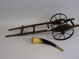 an antique wooden wagon with a brush next to it on a white surface