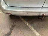 a white car with a rusted exhaust pipe on the back of it